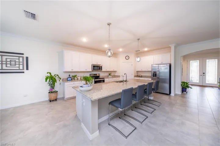 Kitchen featuring white cabinets, stainless steel appliances, an island with sink, and breakfast bar