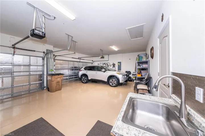 Garage with sink, a garage door opener, and electric panel