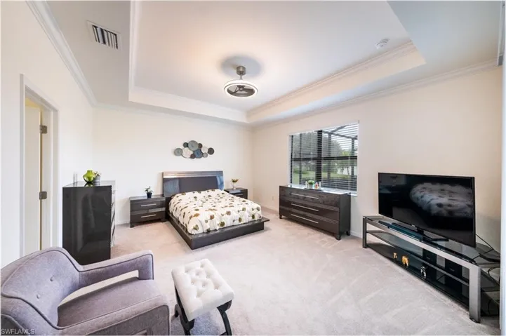 Bedroom with a tray ceiling, crown molding, and carpet flooring