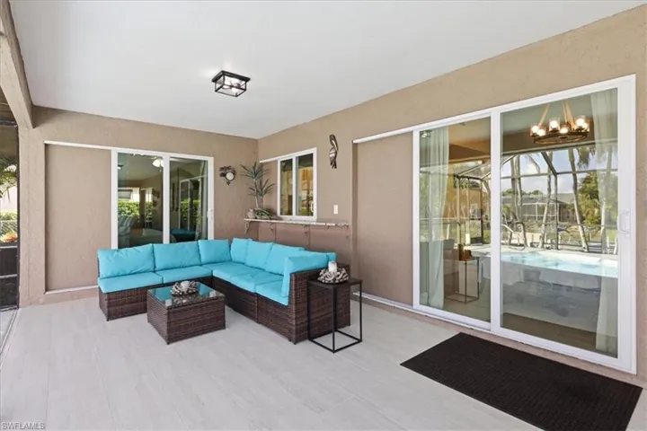 Sunroom featuring outdoor furniture, suspended lighting, and a patio