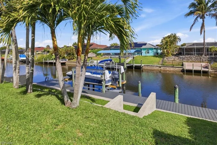 Dock area featuring a yard, a water view, boat lift, and a residential view