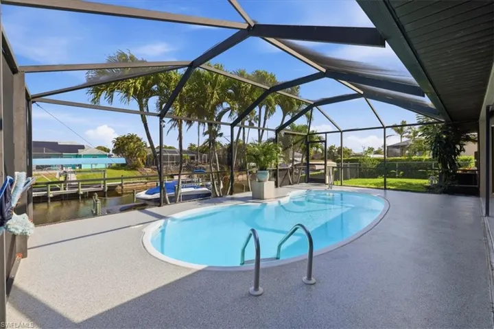 Swimming pool featuring a patio area, a sunroom, and glass enclosure
