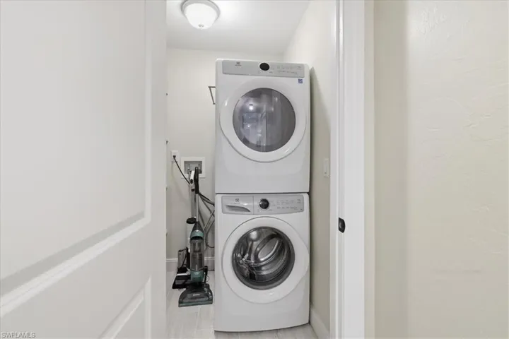 Laundry area with stacked washer / drying machine and a textured wall