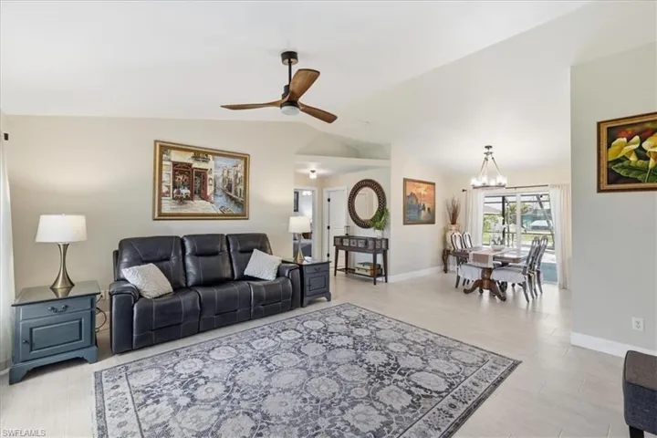 Living room featuring a ceiling fan, vaulted ceiling, suspended lighting, and light wood finished floors