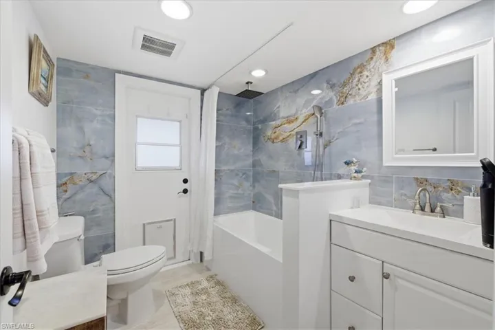 Full bathroom with vanity, tile walls, and a combined bath / shower with rainfall shower