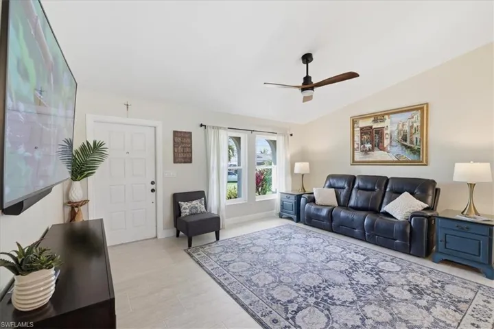 Living area with vaulted ceiling, ceiling fan, and light wood-style flooring