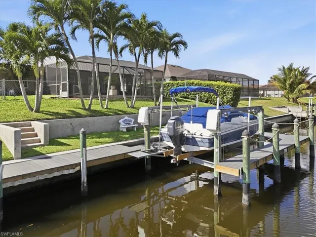Dock featuring boat lift, a lawn, glass enclosure, and a water view