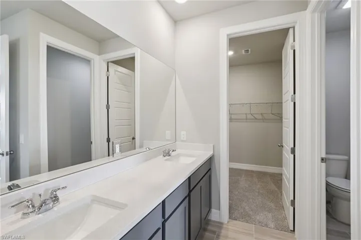 Bathroom featuring double vanity and a walk in closet