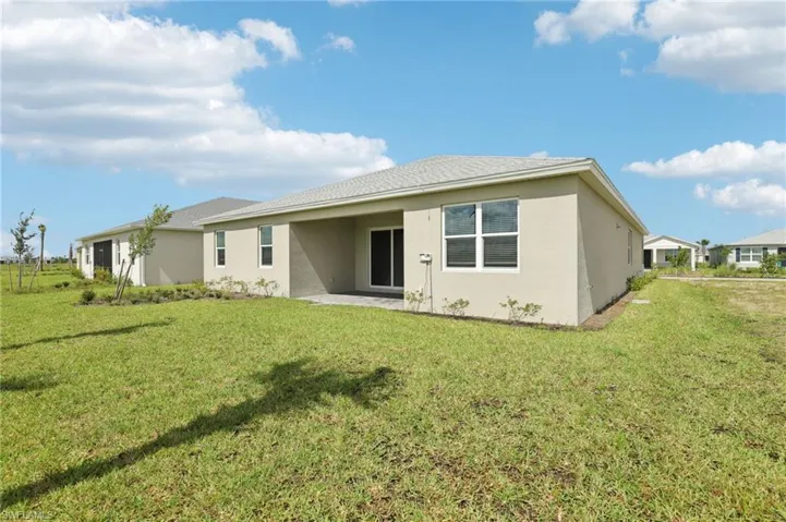 Back of house featuring stucco siding, a lawn, and a patio area
