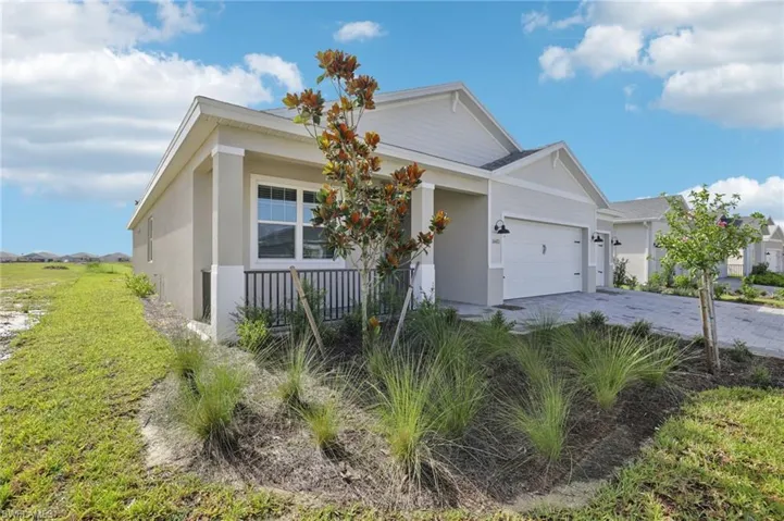 View of front of house with an attached garage, stucco siding, driveway, and covered porch