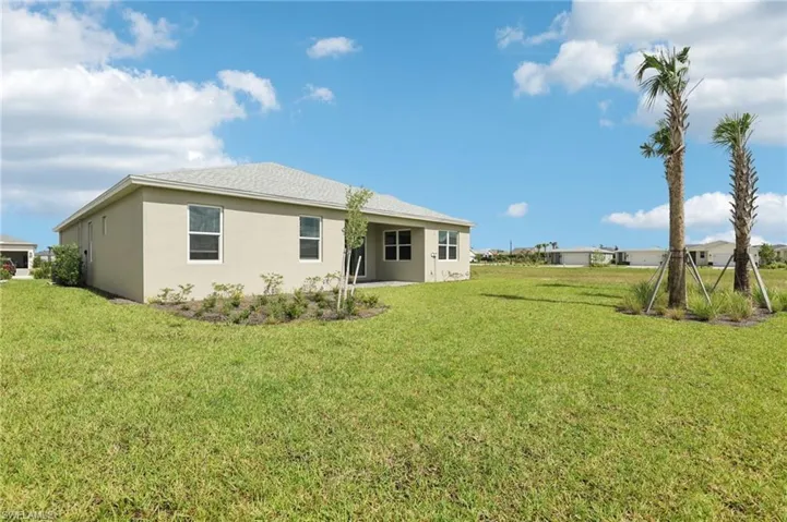 Back of property featuring stucco siding, a lawn, and a shingled roof