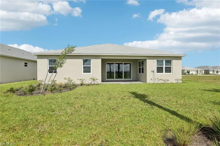 Back of property featuring stucco siding and a lawn