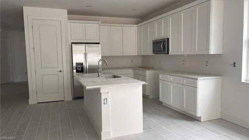 Chef's kitchen with quartz countertops, soft-close cabinets and drawers, and Whirlpool stainless steel appliances including gas oven, range microwave, dishwasher, and 36" side-by-side refrigerator