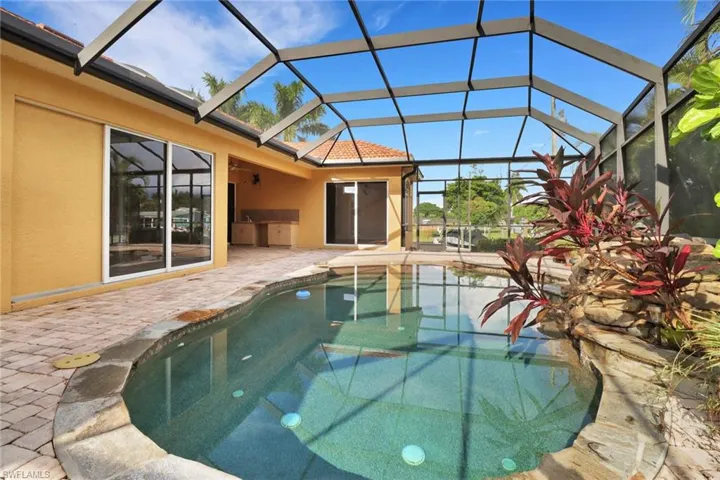 View of pool with glass enclosure and a patio