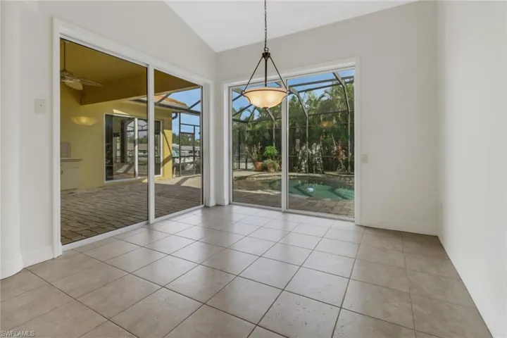 Unfurnished dining area featuring ceiling fan, vaulted ceiling, and light tile patterned floors