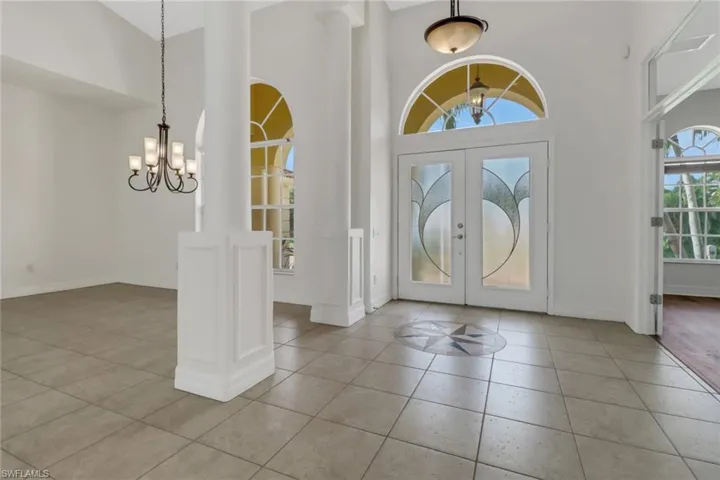 Tiled entryway with a towering ceiling, an inviting chandelier, and french doors