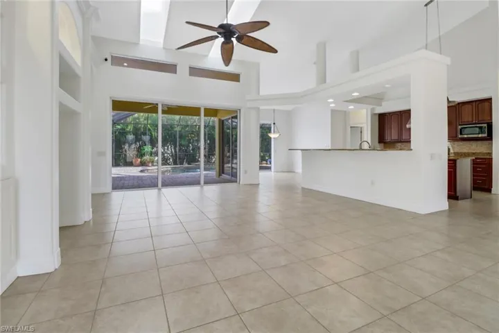 Unfurnished living room with a high ceiling, ceiling fan, and light tile patterned floors