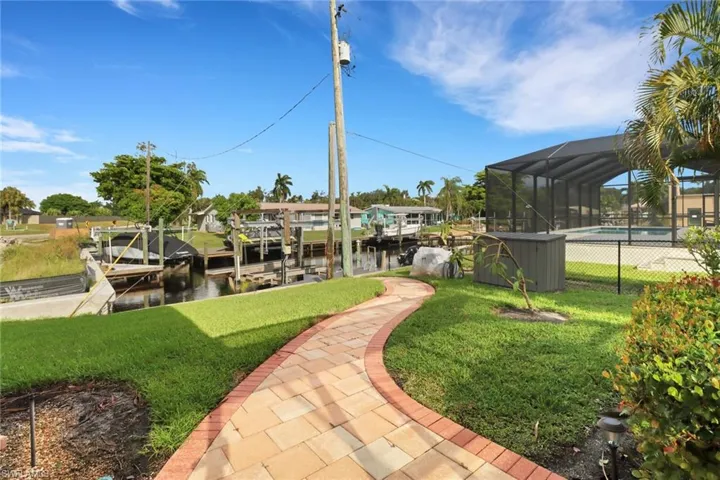 View of community with a yard, a boat dock, a pool, and a water view