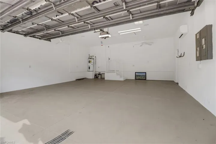 Garage featuring ceiling fan, a garage door opener, electric water heater, and electric panel