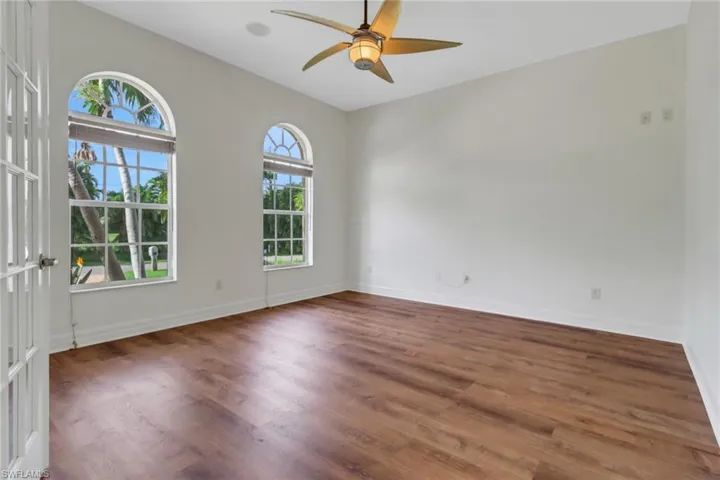 Spare room with ceiling fan, dark wood-type flooring, vaulted ceiling, and french doors