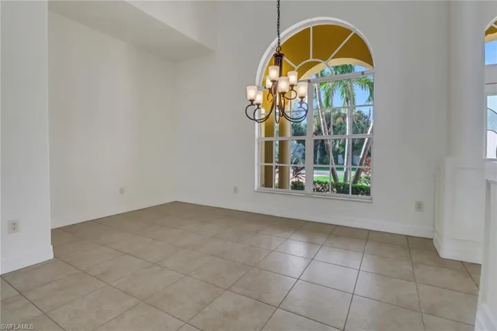 Tiled empty room featuring a healthy amount of sunlight and a chandelier