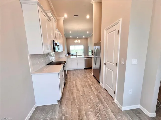 Kitchen featuring white cabinetry, sink, pendant lighting, light hardwood / wood-style floors, and appliances with stainless steel finishes