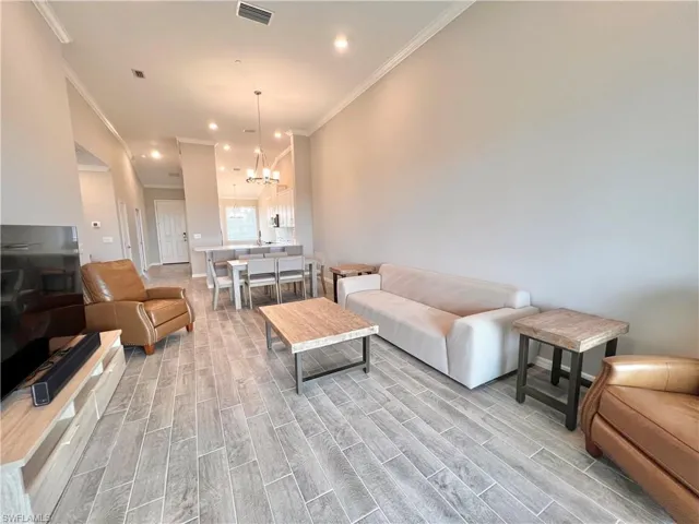 Living room featuring crown molding and a chandelier