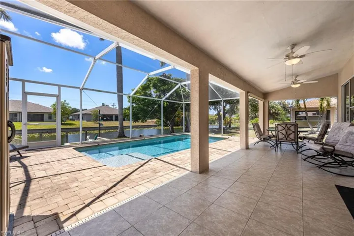 Screened lanai featuring a swimming pool, canal frontage, and covered patio with ceiling fans