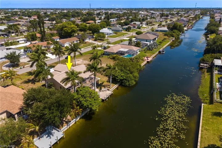 Waterfront property featuring a private dock, screened lanai, mature palm trees, and a canal-front location
