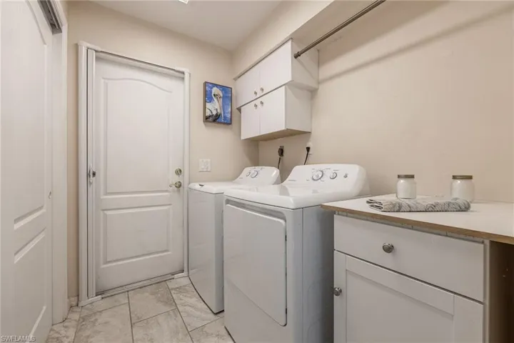 Laundry room featuring tile flooring, white shaker cabinetry, a built-in countertop, and a clothes hanging rod