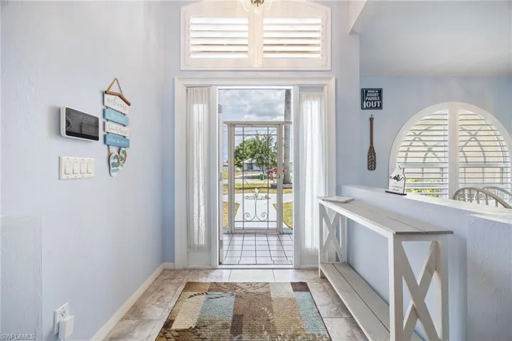Entryway featuring a decorative wrought-iron security door and transom window with white plantation shutters