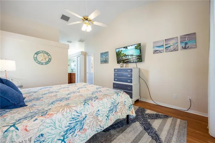 Vaulted ceiling bedroom with light-toned wall finishes and wood-finish flooring