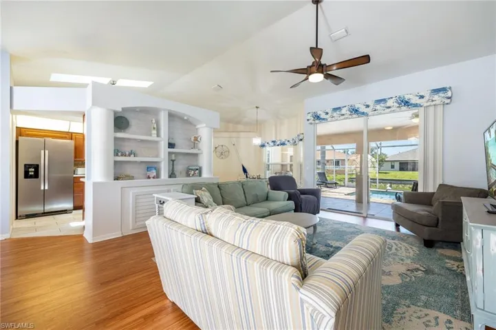 Living area featuring wood-finish flooring, a ceiling fan, and sliding glass doors opening to the screened lanai