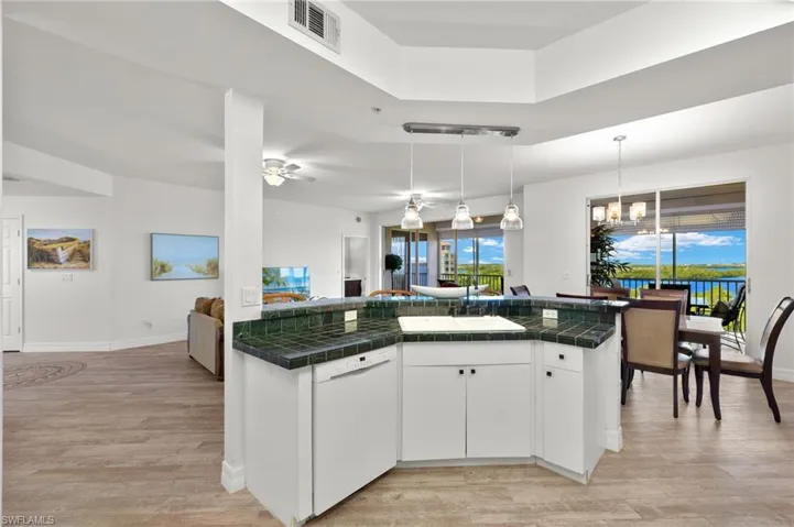 Kitchen featuring dishwasher, light hardwood / wood-style floors, ceiling fan with notable chandelier, tile countertops, and white cabinetry