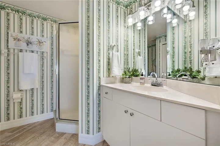 Bathroom with vanity, an enclosed shower, and wood-type flooring