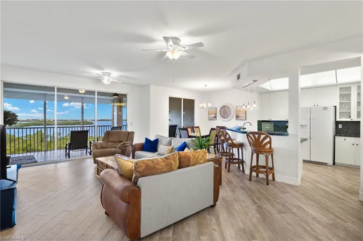 Living room featuring light hardwood / wood-style floors, a water view, and ceiling fan with notable chandelier