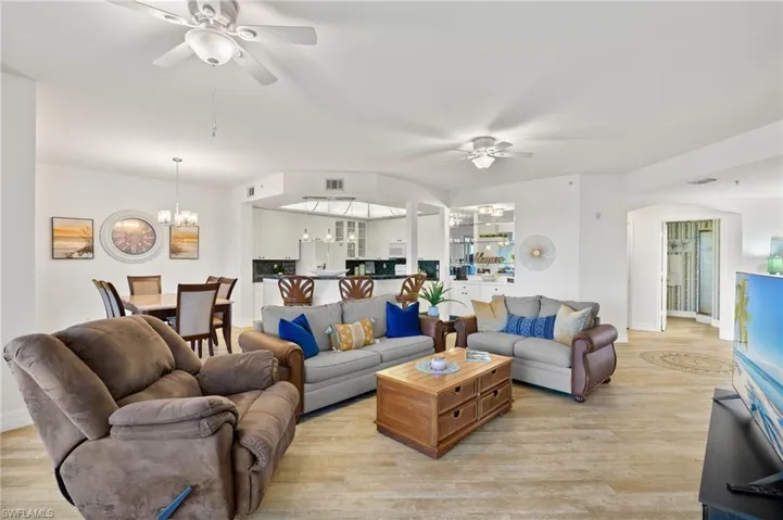 Living room featuring ceiling fan with notable chandelier and light wood-type flooring