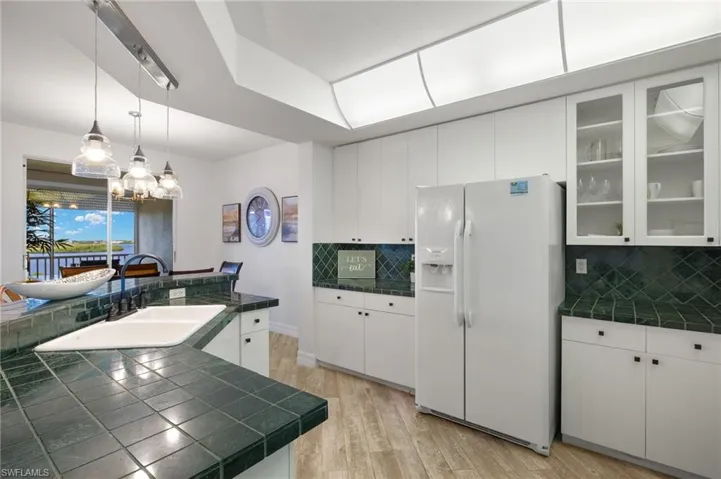 Kitchen with white cabinets, sink, light hardwood / wood-style floors, backsplash, and white refrigerator with ice dispenser