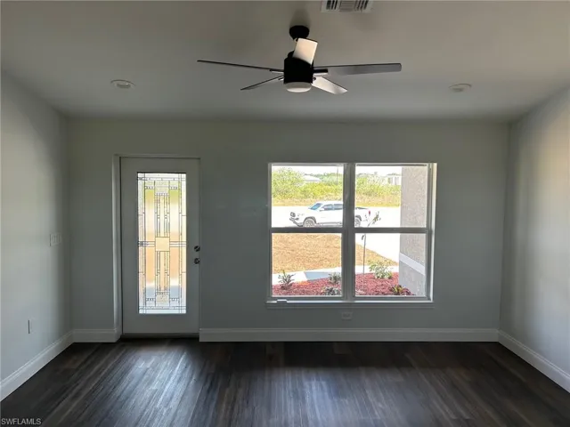 Empty room featuring dark hardwood / wood-style flooring and ceiling fan