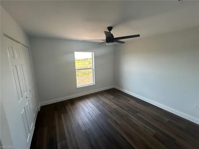 Empty room featuring ceiling fan and dark hardwood / wood-style floors