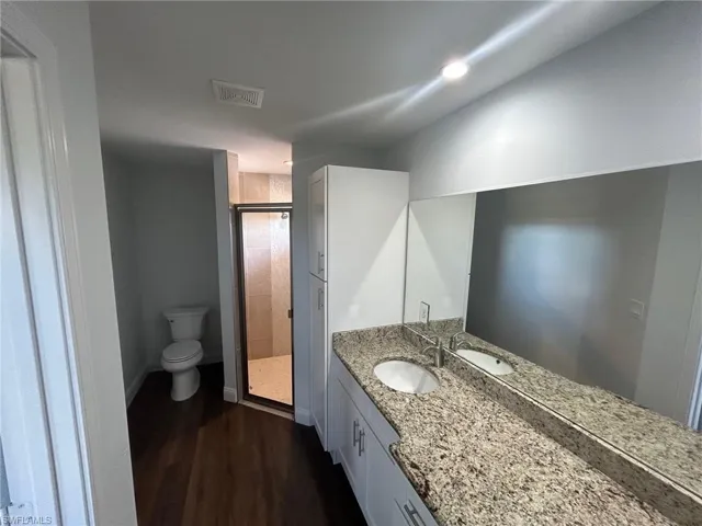 Bathroom with walk in shower, hardwood / wood-style flooring, oversized vanity, and toilet