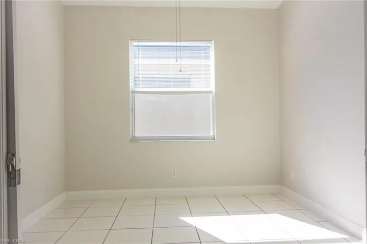 Unfurnished room featuring light tile patterned floors and baseboards