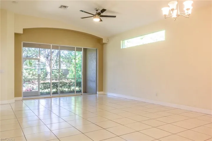 Empty room with light tile patterned floors, a ceiling fan, and a chandelier