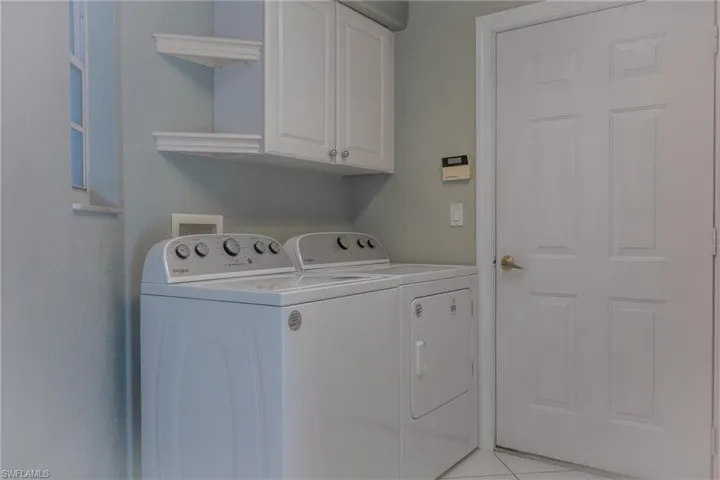 Laundry area with independent washer and dryer, cabinet space, and light tile patterned floors