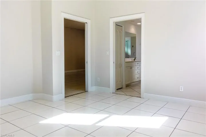 Unfurnished bedroom with light tile patterned floors and ensuite bathroom