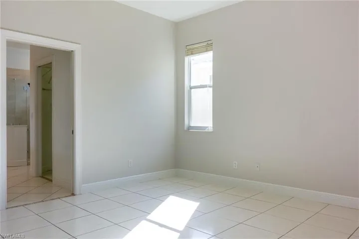Empty room featuring light tile patterned floors and baseboards