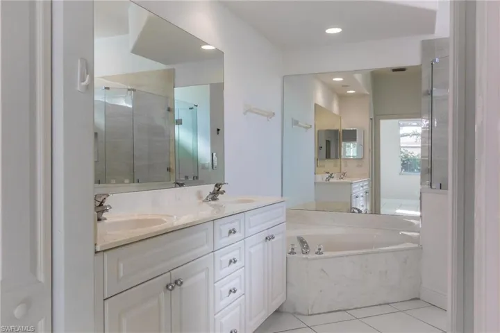 Bathroom featuring a garden tub, double vanity, a stall shower, light tile patterned floors, and recessed lighting