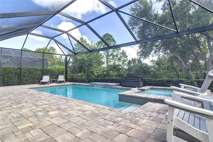 Beautiful pool/spa with a picture view screen and a large sun lounge a patio