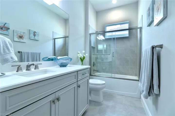 Guest bathroom with shower/bath combo with glass door, vanity, and a linen closet