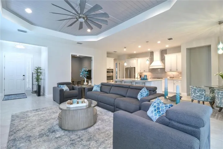 Living room with wooden ceiling, a raised ceiling, sink, and ceiling fan